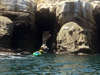 Kayak paddling through the sea cave passage in the sea cliffs near La Jolla Cove.