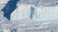 Melting glacier with ice cliff and sea ice in Antarctica.
