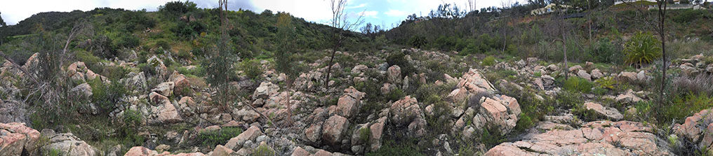 Another panoramic view of a large field of boulders and outcrop of orange and white colored rocks of the San Dieguito River floodplain.