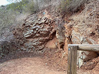 Brown, fracture basalt outcrop in a cut in the bend of a trail switchback.