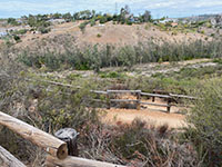 View looking down as series of fence-line trail switchbacks with the San Dieguito River valley in the distance.