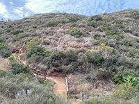 View of a series of fence-lined switchbacks on a hillside covered with a coastal sage scrub plant community