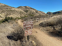View of the Del Dios Gorge Trail with a sign, with the gorge in the distance.