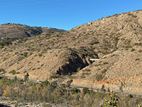 View of the mountainside above the Del Dios Highway with part of a pipeline exposed below a stream terrace.