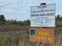 A sign for trail park showing parking area hours.