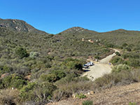 View looking uphill at the Del Dios Preserve trailhead parking area and the Del Dios Trail heading off into the chaparral-covered highlands.