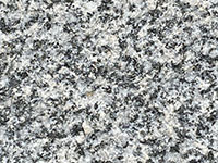 A zoomed in view of a crystalline igneous rock surface showing interlocking white, gray, and black crystals.