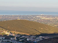 View of San Marcos Peak with the microwate tower on top. The smoke stack in Carlsbad is visible in the distance.