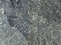 Close-up view of a dark, fine grained volcanic rock that could be called either andesite or basalt