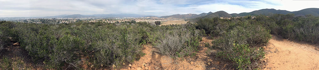 Panoramic view of the chaparral and sagebrush covered upland of Cerro de las Posas ridgeline with a sweeping view extending from the coastline near Oceanside to the rolling ridgelines of the San Marcos Mountains including Mt. Whitney, Franks Peak, and Double Peak.