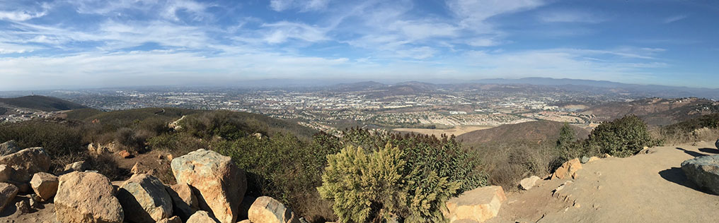 Panoramic view that encompasses the chaparral-covered ridgeline of Cerro de las Posas with the urbanized low plateau region between San Marcos and the coastline along Carlsbad and Oceanside.