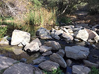 Angular boulders in a shallow creek bed at the crossing.