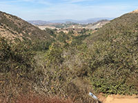 V-shaped San Elijo Gorge valley with forest in the bottomland and chaparral-covered mountain slopes.