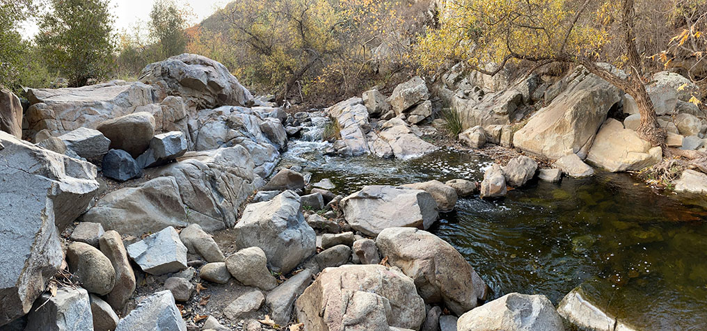 Large rock outcrops and boulders along Escondido Creek, low flow, with a dark pool.