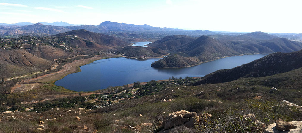 Zoomed-in panoramic view of Lake Hodges in the Del Dios Gorge surrounded by mountainsides along the lake with mountains in the distance.