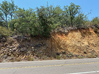 A fault strand offsets alluvial gravel deposits next to deeply weathered and fractured bedrock exposed in a cut along South Grade Road.