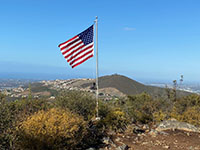 Unfurled UA flag on a pole on the top of Franks Peak with Double Peak in the distance.