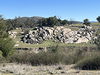A large outcrop of fracture granite exposed on a slope in the grasslands.