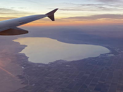 View looking out a airplane window pas a wing with the Salton Sea in the distance