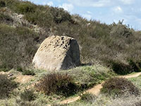 A large, weathered boulder rosies above the sagebrush along the Highland Valley Trail.