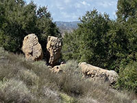 An outcrop of granite with two large head-shaped boulder balanced on top that had obviously split apart in the past.