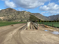 The path of the San Pasqual Valley Trail is restricted between two fences through the agricultural fields in the valley.