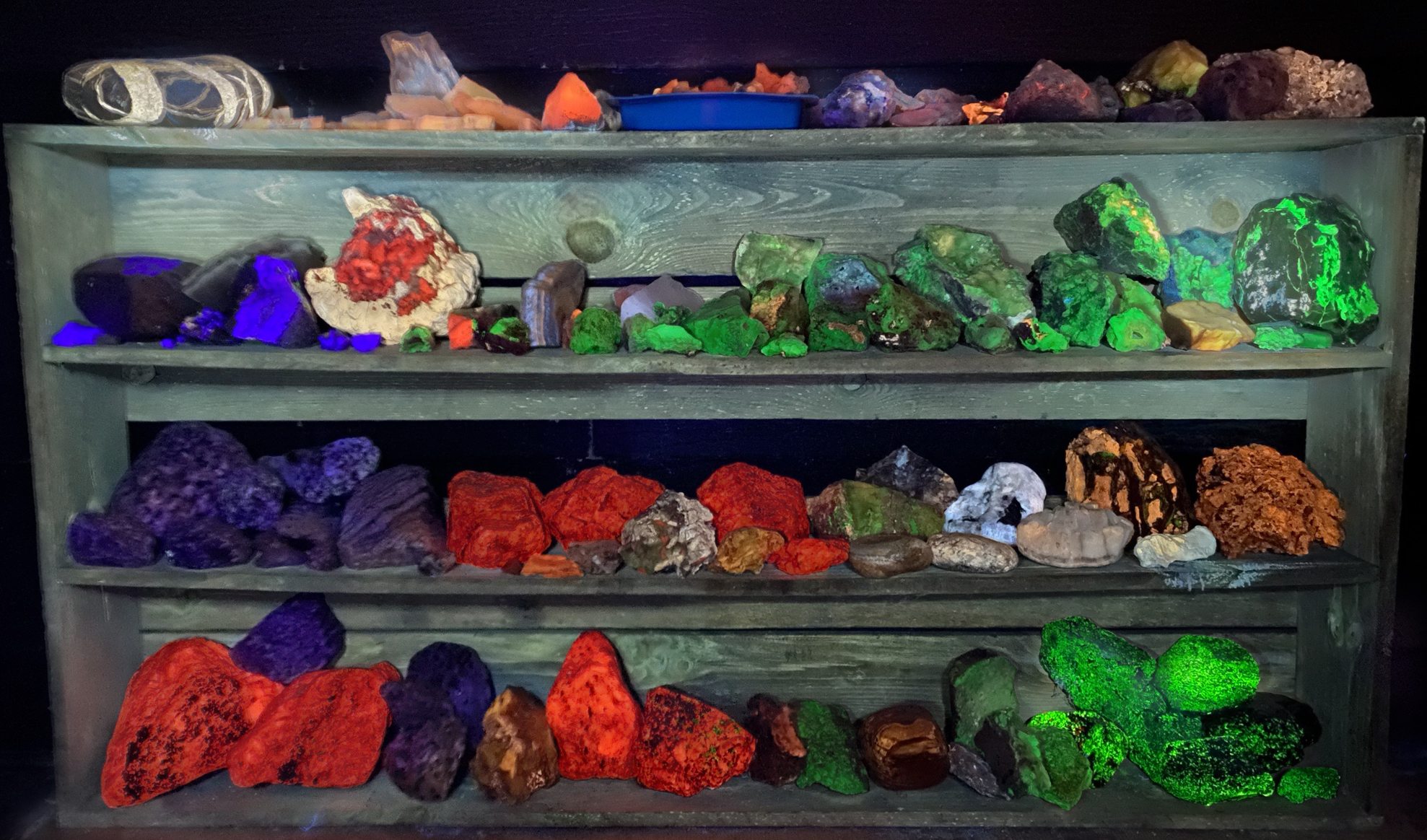 4 shelves of rock and  minerals samples under a mix of Bands A + B + C ultraviolet  lighting with slightly longer exposure.