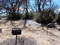 A picnic area grill next to granite outcrop with morteros.