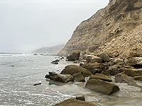 Massive blocks of rock cover the narrow beach below the Scripps Formation exposed in the sea cliff near Dike Rock.
