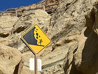 Signs with the universal symbol for rockfall hazards along seacliffs are posted warnings in the park.