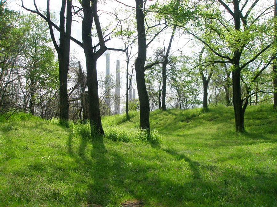 View of the path among the ancient earthworks along a trail in Shawnee Lookout Park. Smoke stack from a power plant are in the distance.