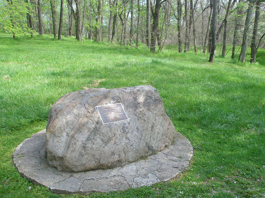 A glacial erratic (boulder) is used to hold a historic marker