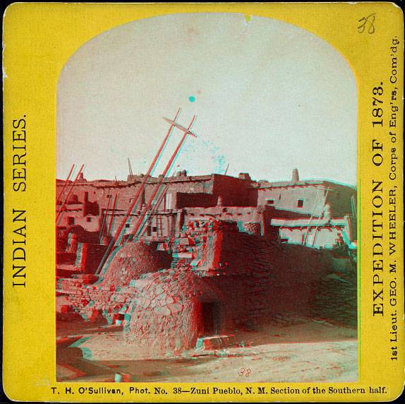 Adobe buildings with ladders and two low, round cooking kilns.