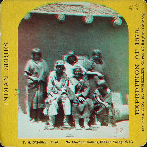 Six people posed in full native dress in front of a building