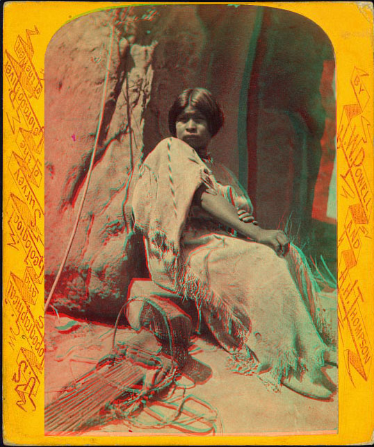 A woman in native dress sitting in front of a rock