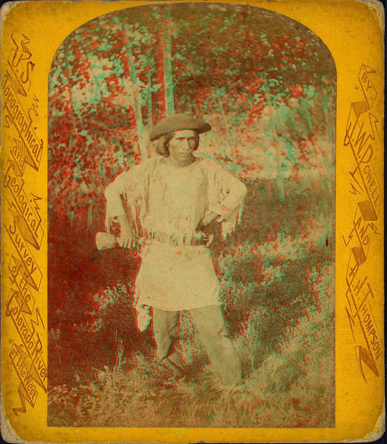 A man in native dress standing outside, wearing a funny hat