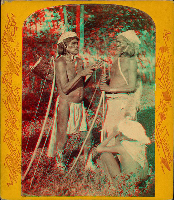 Two men in native dress holding bow and arrows, and a child sitting