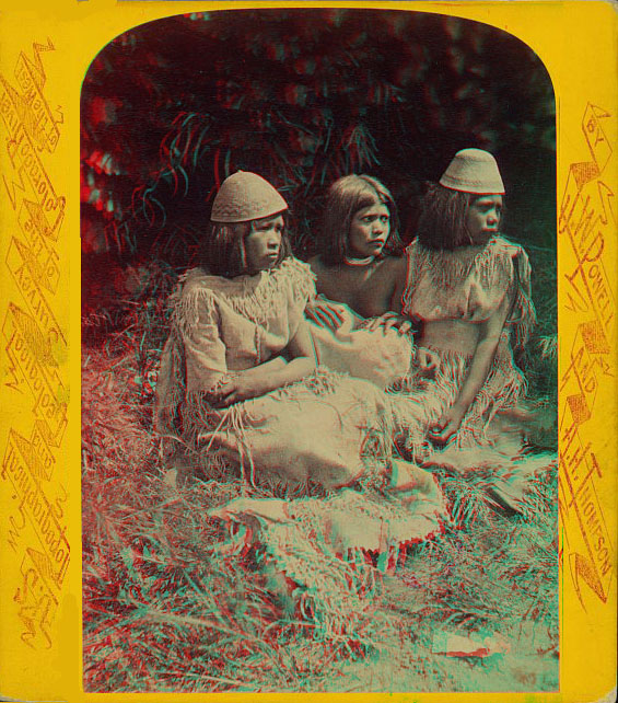 Thee women in native dress sitting. Two are wearing hats