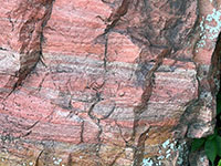 Finely laminated and crossbedded layers in the colorful (reds) Souix Quartzite Formation of Precambrian age exposed in an outcrop along the park loop trail in Pipestone National Monument.