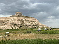 Wagon train on display on the Oregon Trail through Mitchell Pass with Sentinal Rock near the Visitor Center.